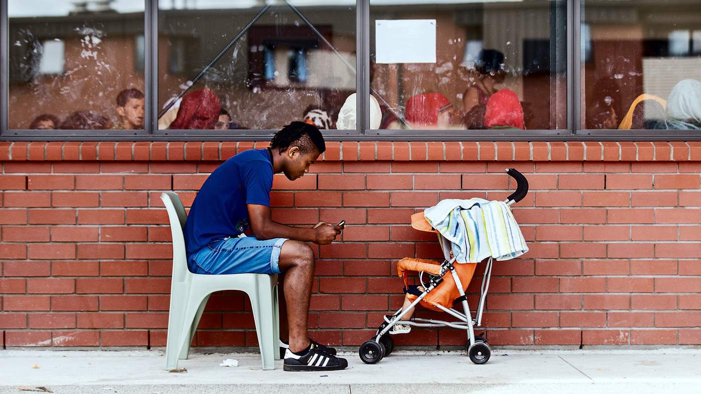 Cristian Cuero, 17, checks his phone as he looks after a baby outside a group meeting at the Mangere Refugee Resettlement Centre.