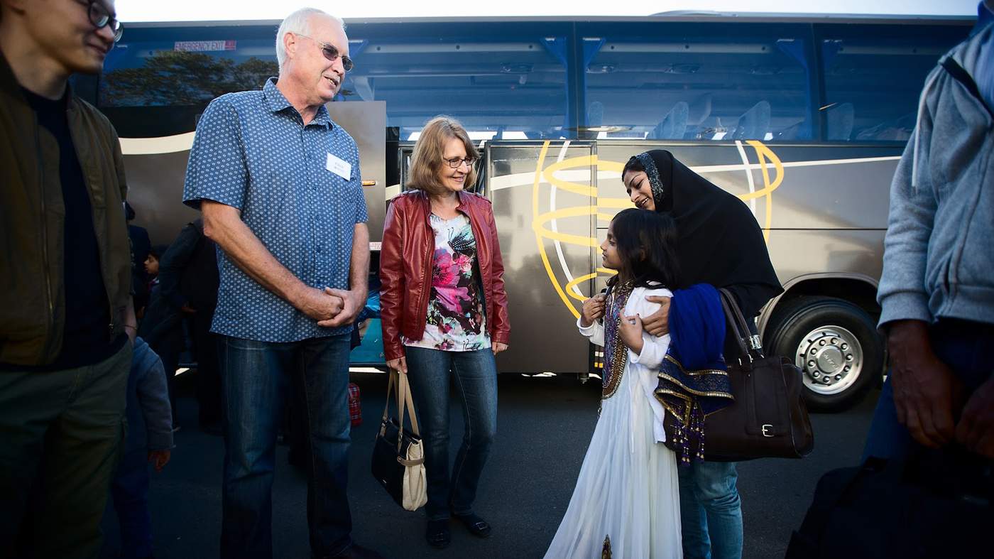 Red Cross volunteers Chris and Frouke Nicholson welcome the new arrivals off the bus from Auckland. Over the next year they’ll help smooth the family’s integration into Hamilton life. 