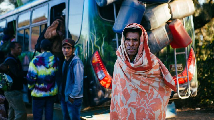 A villager  in a blanket about to catch the bus in Letefoho