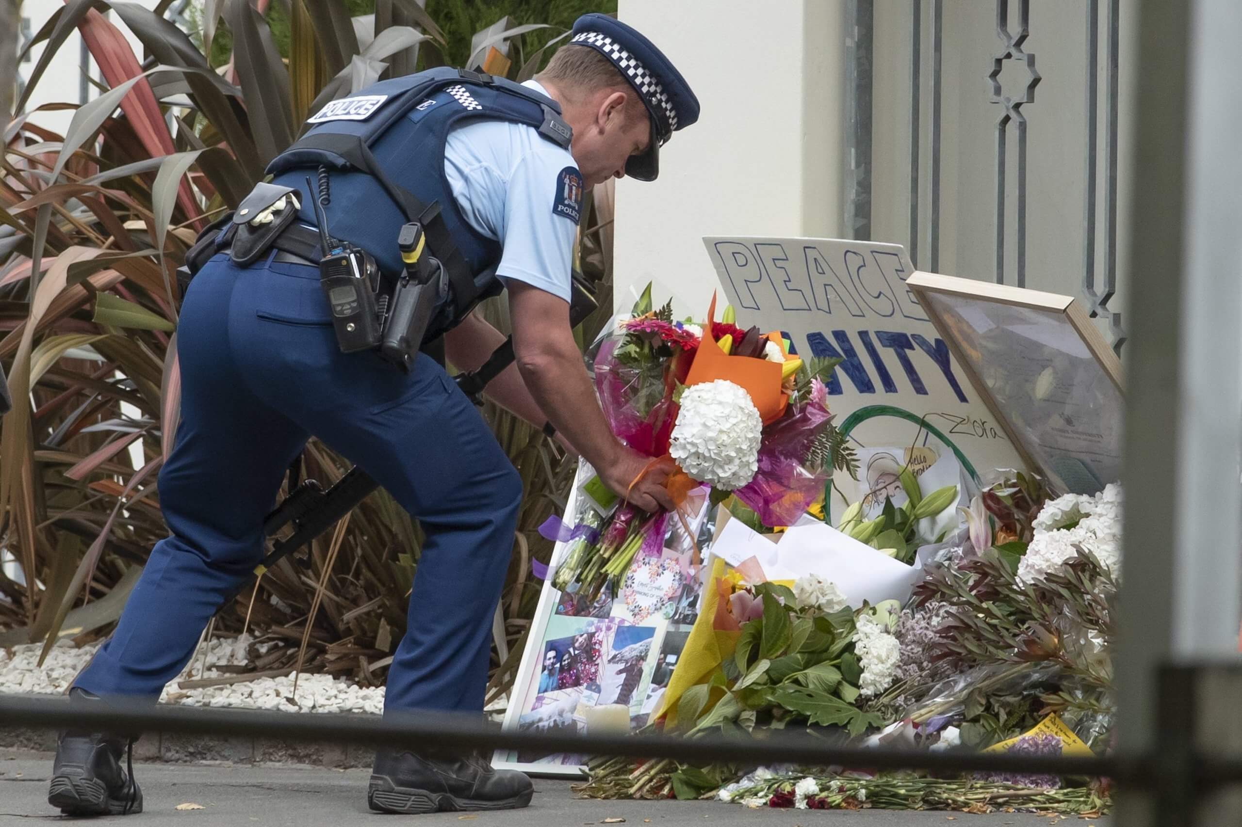 A policeman takes flowers to Christchurch's Al Noor Mosque. Credit: Iain McGregor / STUFF