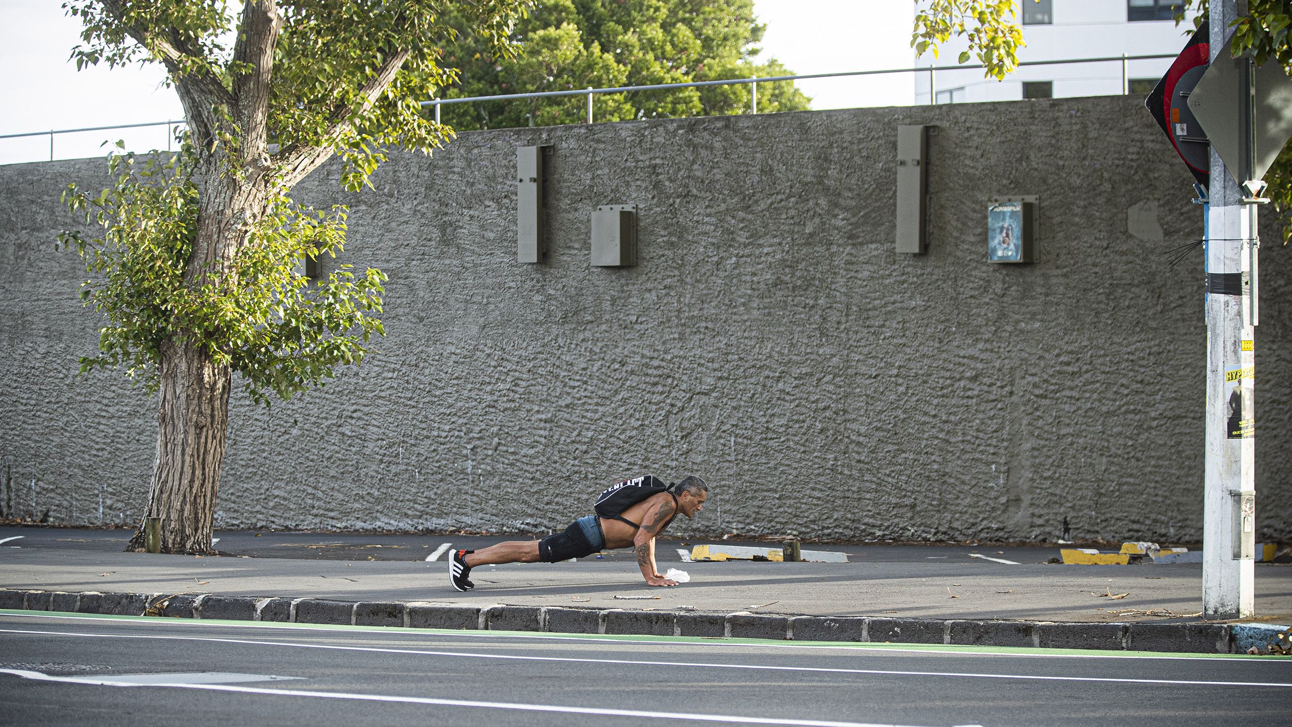 Man doing press ups on the sidewalk.