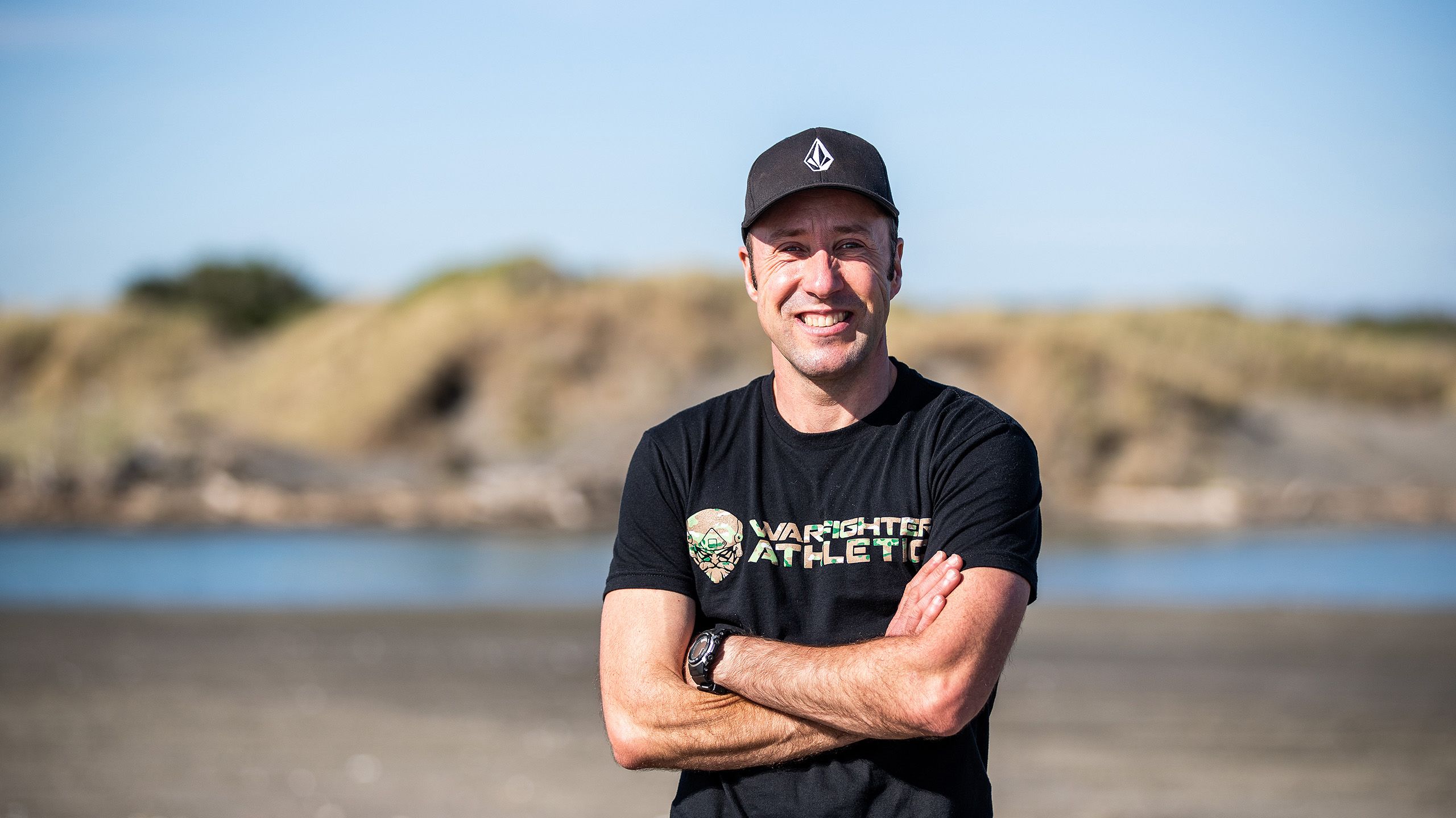 Mark looks straight to camera with his arms folded.
