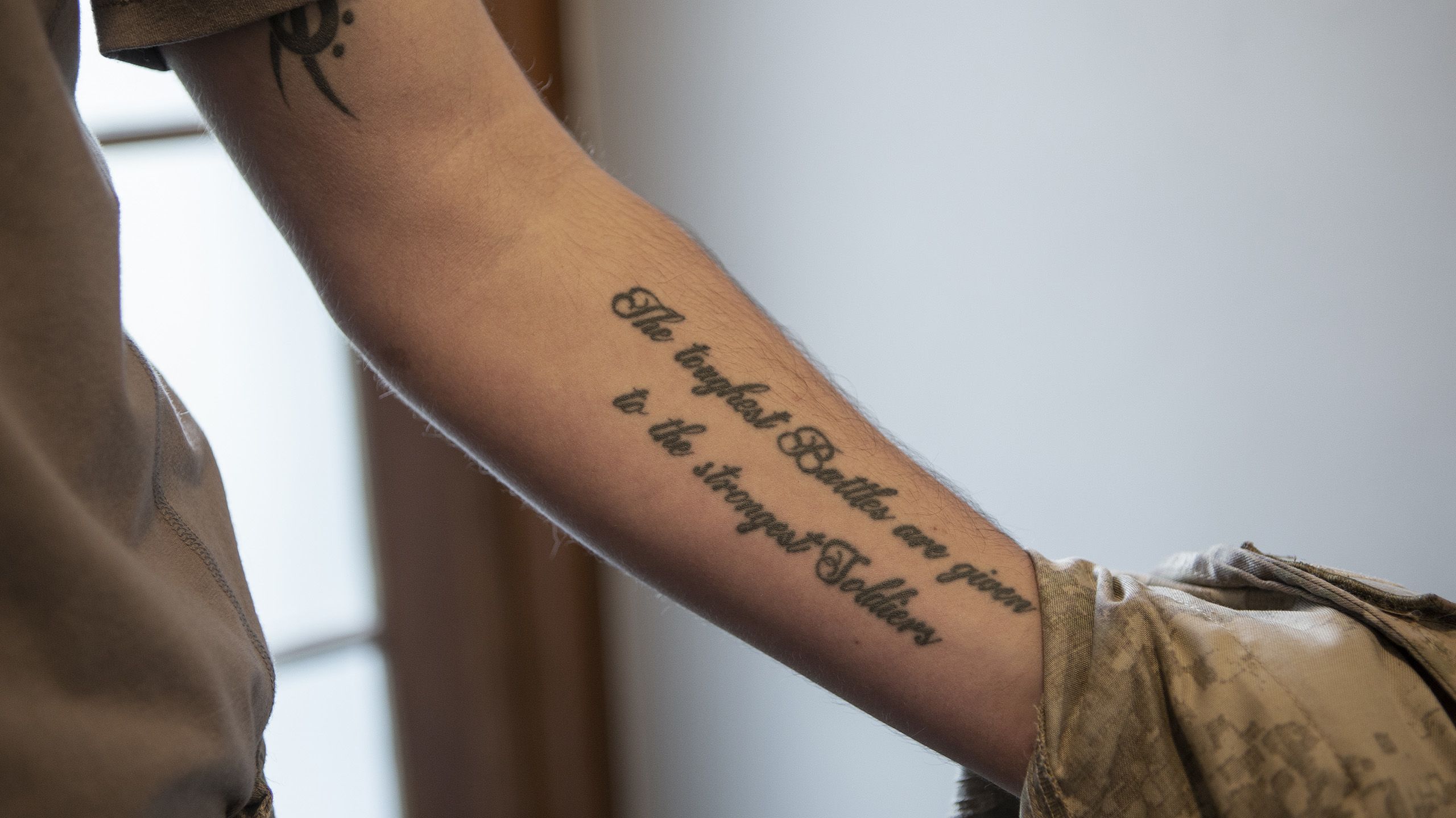 Close-up of Sawyer's tattoo on his arm, which says "The toughest Battles are given to the strongest Soldiers".