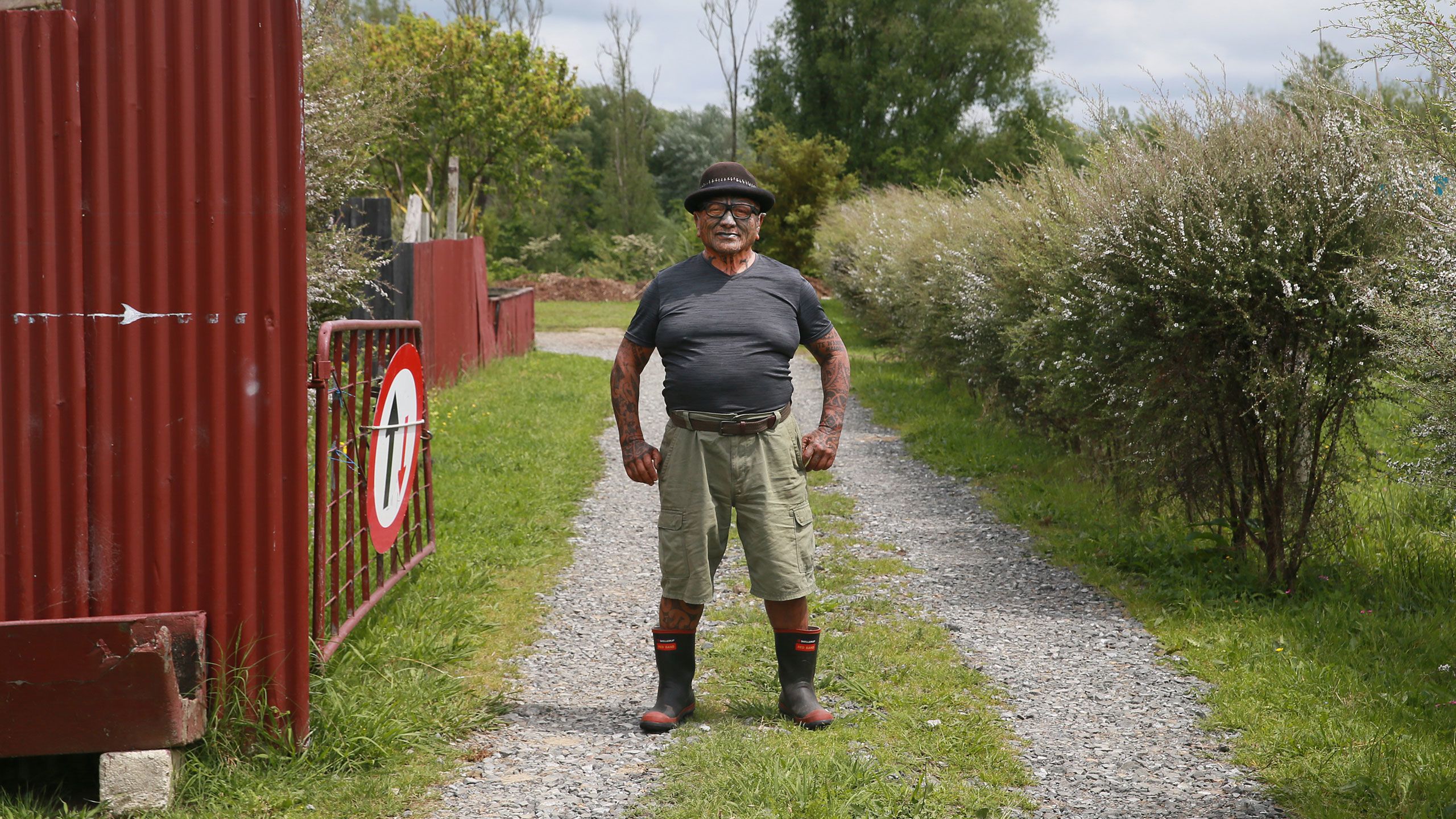 Tame Iti standing in his driveway, hands next to his sides.