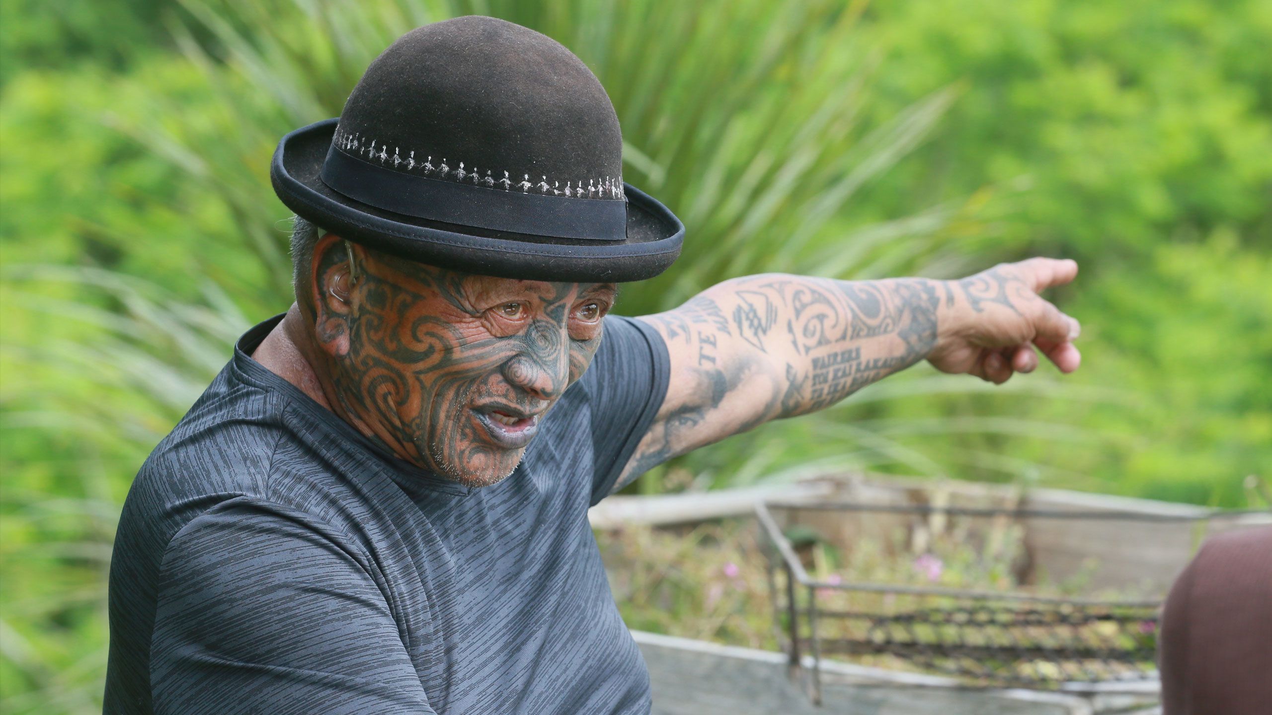 Tame outside his home, with his left arm raised with his finger pointing.