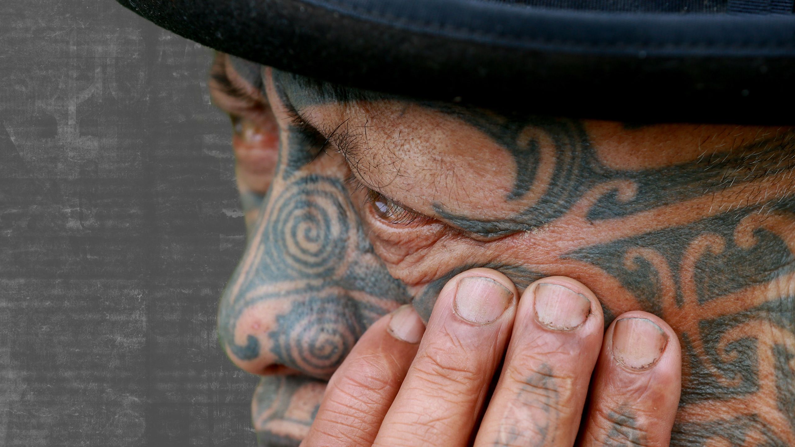 Close-up of Tame's face, hand on his cheek, looking pensive.