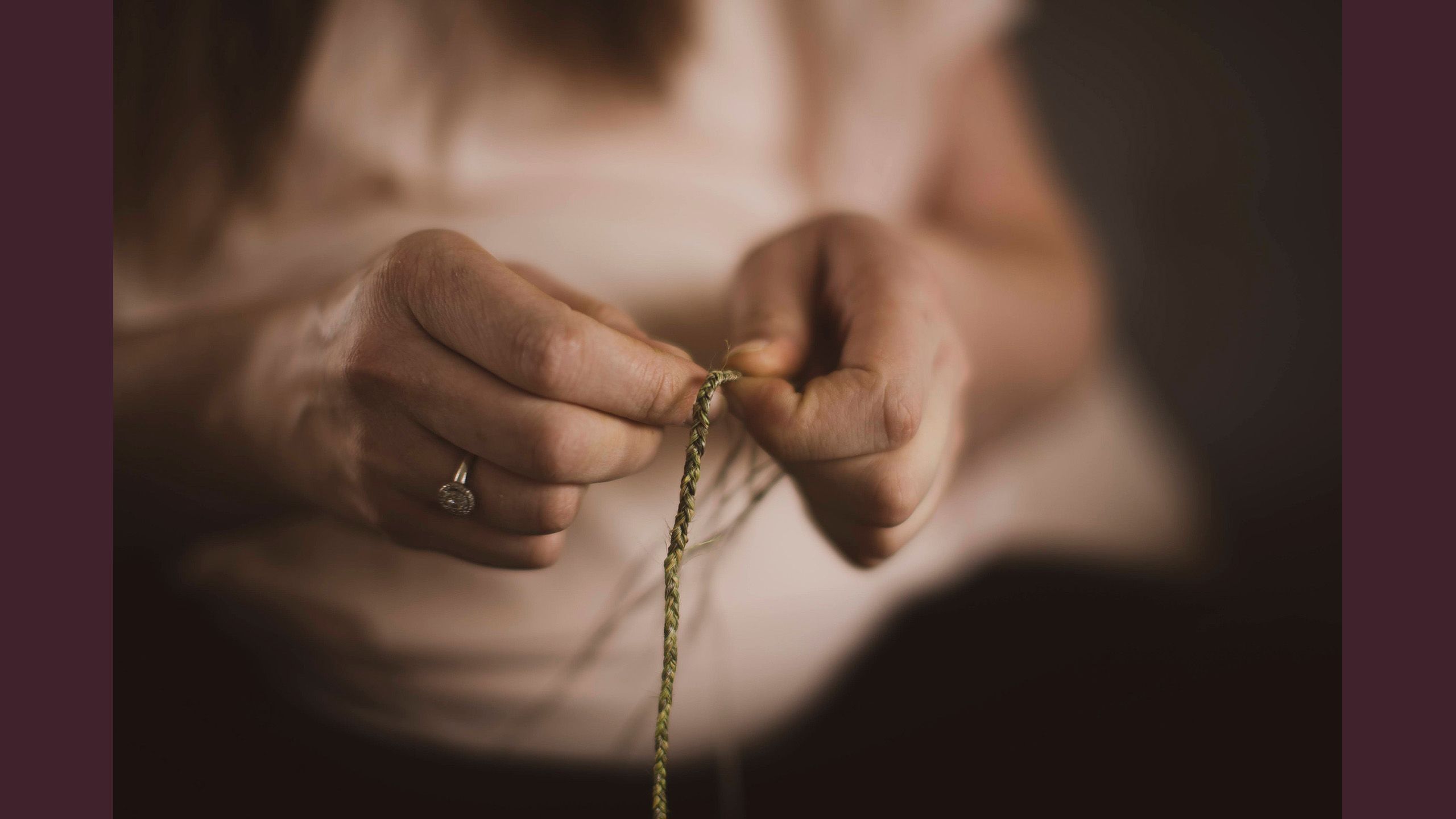 A close-up of Jessica's hands weaving the harakeke.