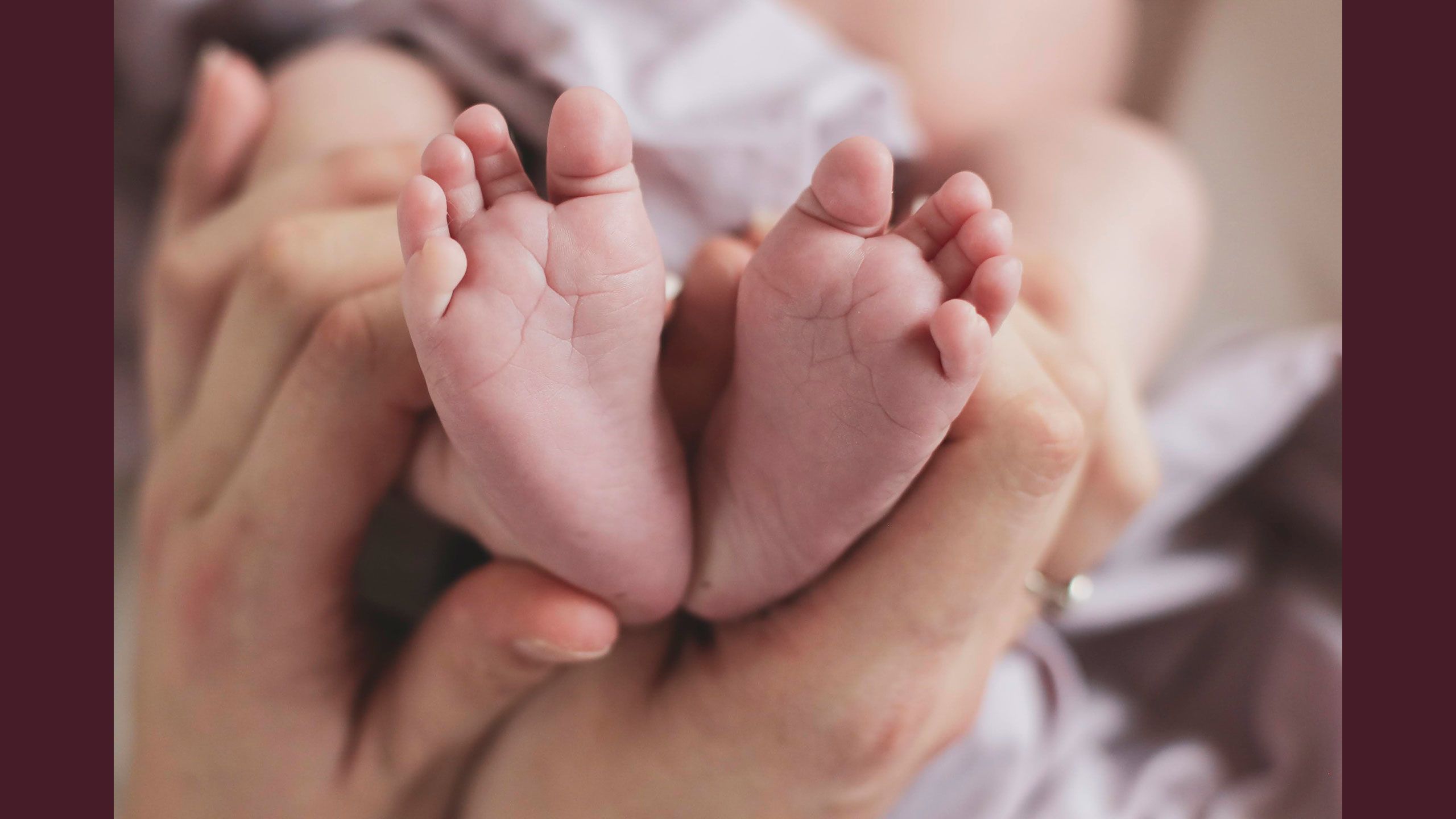 Jessica holds onto Hazel's feet which are facing upwards showing the bottoms, creating heart shape.