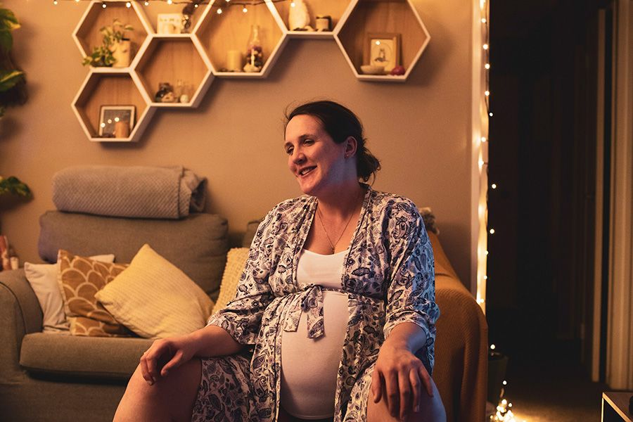 Jess sits smiling on a Swiss ball in her front room at the start of her labour.
