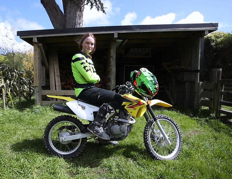 Charlotte sits with her arms folded on her dirt bike.