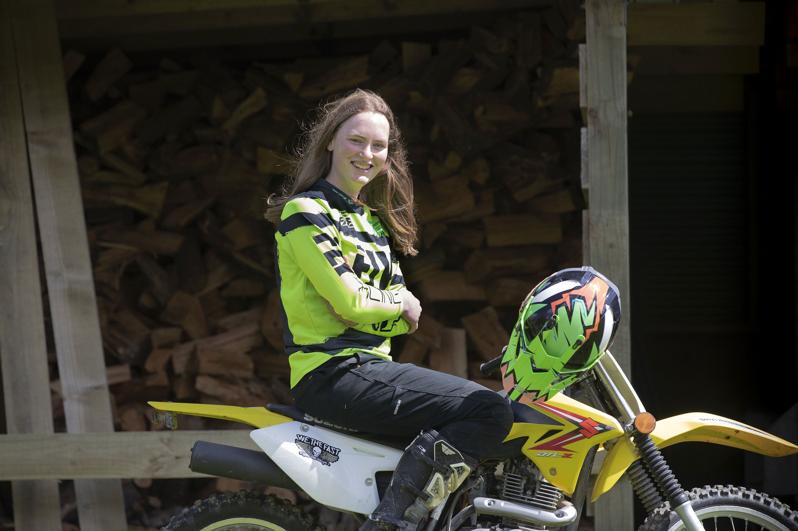 A smiling Charlotte sits on her dirt bike.
