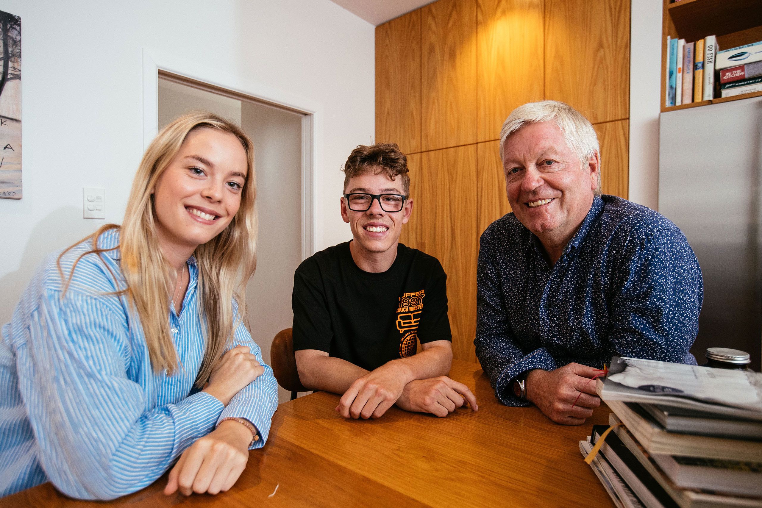 Fully gown India and Mac sitting at a table with their father, David.and