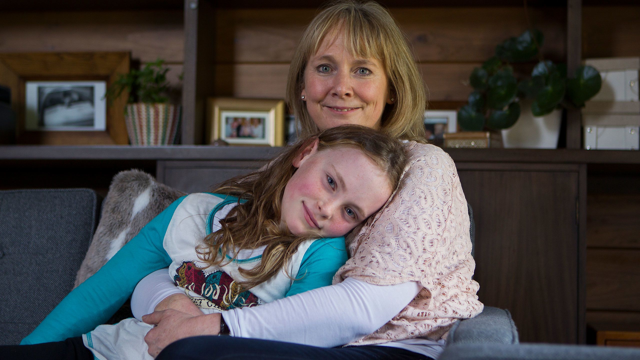 Liz Rose cuddles Charlotte on the sofa. Charlotte is about eight years old.