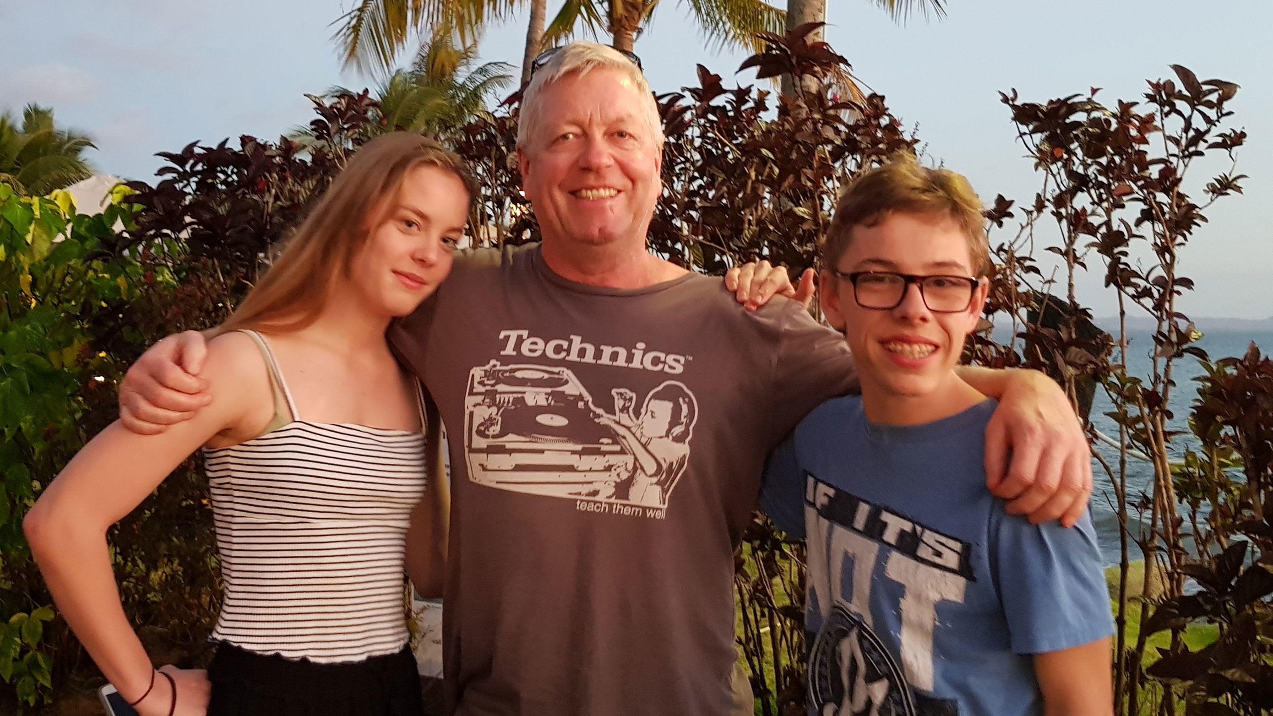 Father, David, stands embracing India and Mac who are either side of him.