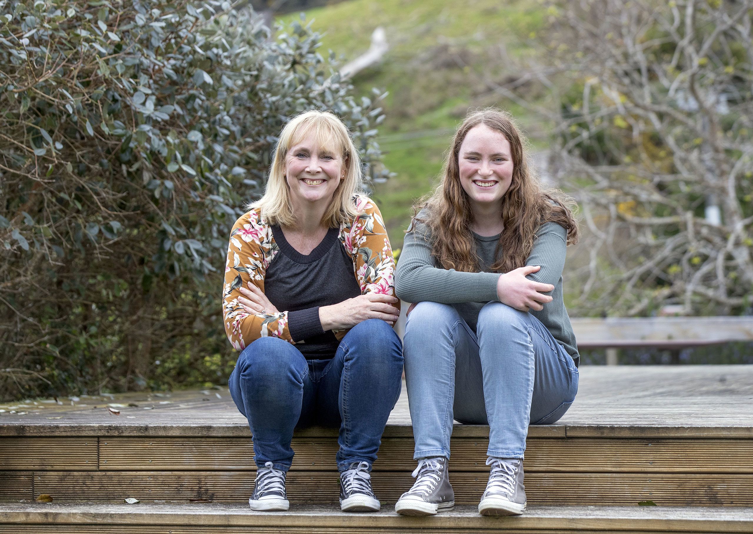 Liz and Charlotte sitting together on the step of their deck at home.