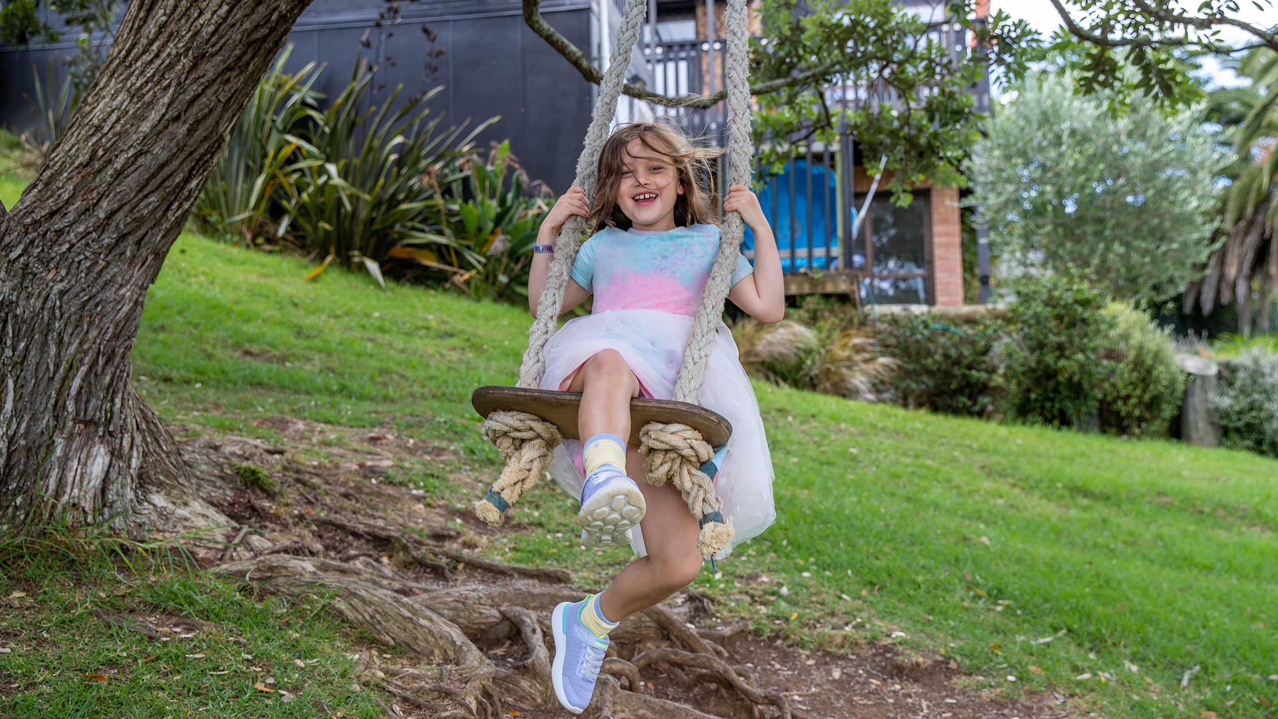 Evangeline is swinging on a rope swing at the park. 