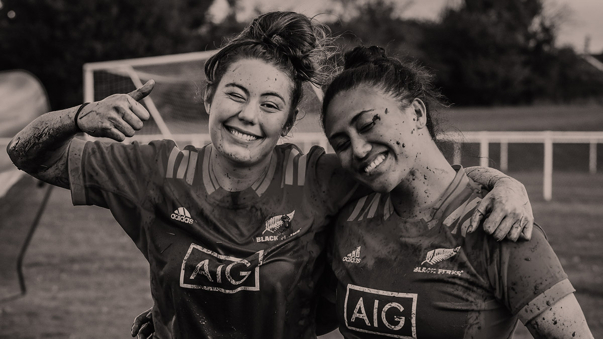 Two mud-splattered female rugby players